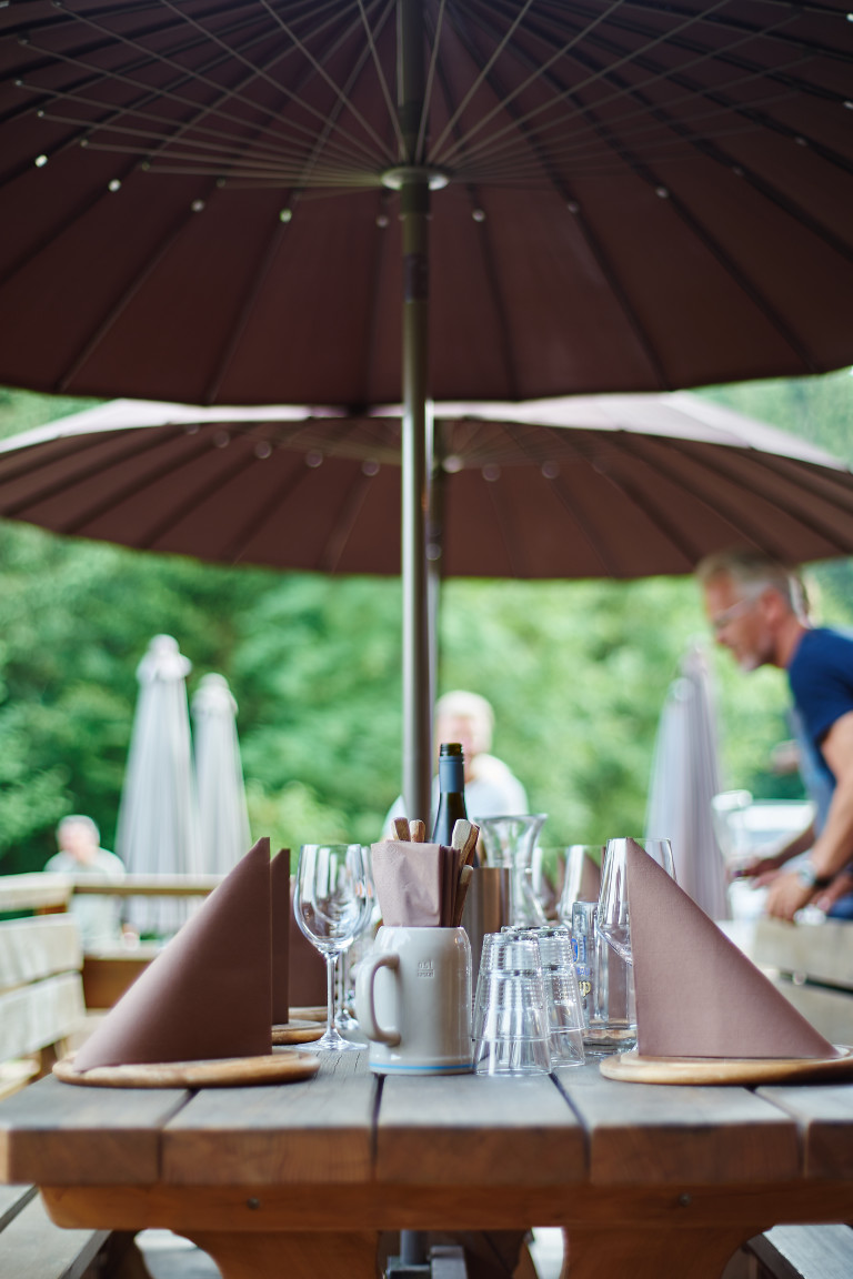 Gedeckter Tisch mit gespannten braunen Sonnenschirmen auf der Terrasse des Almbad Huberspitz