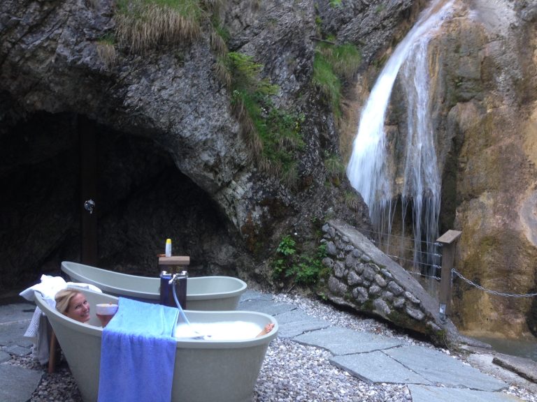 Frau entspannt in Outdoor-Wanne des Dorfbad Tannermühl mit Blick zum Wasserfall
