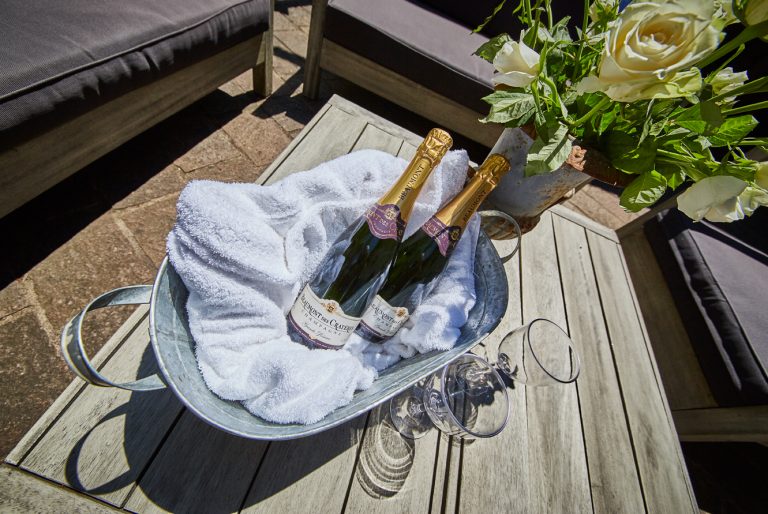 Kühl gestellter Champagner und Rosenstrauß auf dem Tisch der Sonnenterrasse für besondere Anlässe im Dorfbad Tannermühl