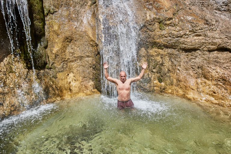 jubelnder Mann vorm Wasserfall im Gumpen-Tauchbecken des Dorfbad Tannermühl