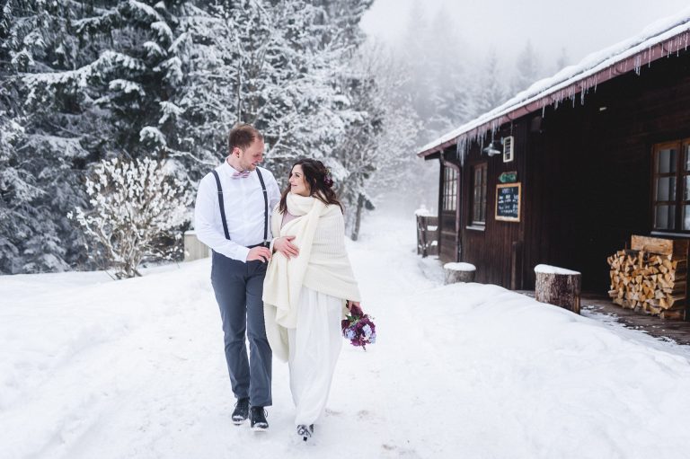 Ein Brautpaar schreitet durch den Schnee zur standesamtlichen Trauzeremonie im Winter